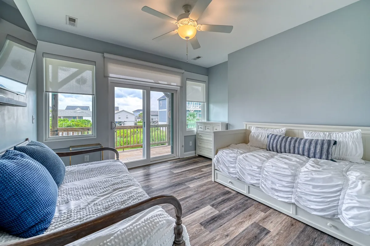 A kid-friendly room highlighted by a cozy daybed with blue accent pillows, expansive windows overlooking the deck, and a tranquil ambiance. The setup is perfect for reading, napping, or enjoying the view.