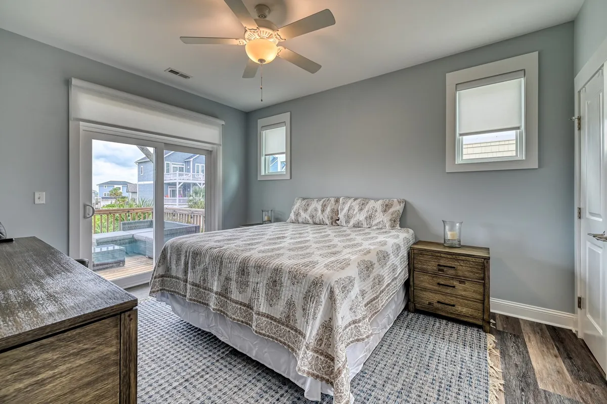 A sunlit bedroom with a welcoming bed, large windows offering scenic views, and a dresser—creating a serene space ideal for reading, relaxing, or simply enjoying the sunrise.