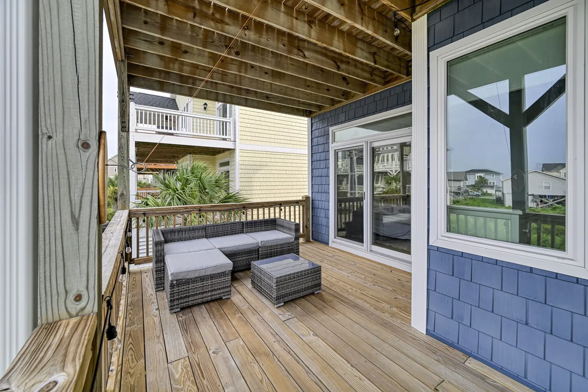 Featuring an inviting outdoor seating area on a wooden deck, this scene is surrounded by greenery. The mood is casual and friendly, ideal for reading, socializing, or savoring a morning coffee in the fresh air. The setting hints at a space where both relaxation and social moments flourish.